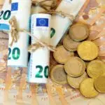 High angle shot of some rolled banknotes and coins on more banknotes
