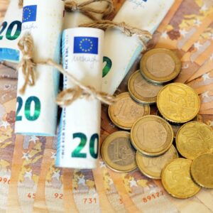 High angle shot of some rolled banknotes and coins on more banknotes